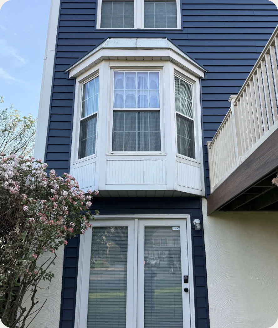 Home with navy siding and a white bay window